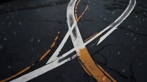 Two painted road arrows crossing on wet asphalt and pointing in opposite directions, representing a reversal of policy