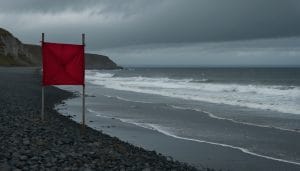 Illustration: empty shingle beach with a red warning flag and an outfall pipe