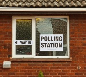 A Polling Station sign and a Way In arrow in the window of a brick building in Minster-in-Thanet, Kent