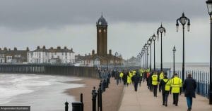 AI-generated illustration of a calm march along a seaside promenade with a clock tower, watched by police officers in high-visibility jackets