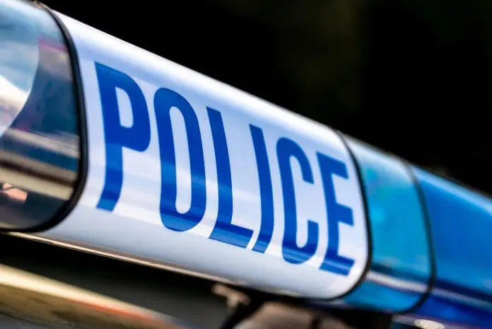 Angled,View,Of,Police,Sign,With,Blue,Lights,Atop,Of